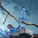 The OhWii Double-Ended Glass Dildo for G-Spot & P-Spot, curvy and transparent blue, lies on a rough gray rock near a bare twisted branch, with a soft blue cloth and blurred blue background.
