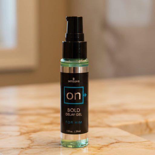 A 1 oz (29 ml) bottle of On Bold Ejaculation Delay Gel For Him sits on a marble surface with a blurred neutral background—designed to help delay ejaculation and safe for use with condoms.