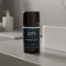 A black bottle labeled "On Power Glide for Him Penis Performance Enhancer," a male arousal gel, sits on a gray bathroom counter, with blurred toiletries and a white container in the background.