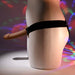 A mannequin showcases the Our First Hollow Strap-On Dildo + Harness Set - Chocolate, highlighted by a vibrant disco light backdrop that accentuates its side profile and flexible TPE shaft.