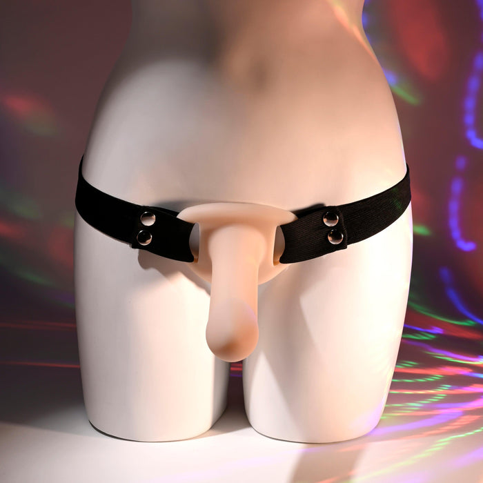 A white mannequin torso features the "Our First Hollow Strap-On Dildo + Harness Set - Vanilla" in black and beige, while a vibrant, abstract light pattern enhances the appeal of this display.