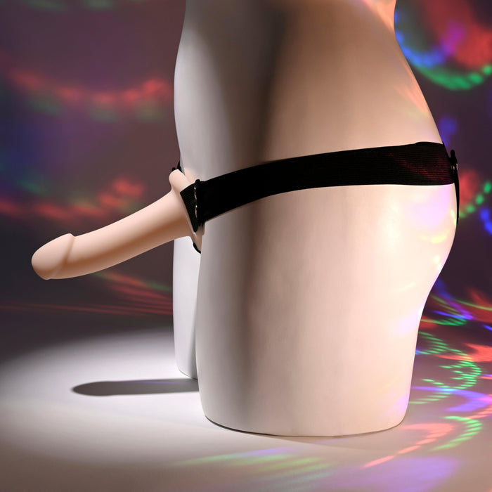 A white mannequin torso displays Our First Hollow Strap-On Dildo + Harness Set - Vanilla. Multicolored lights create abstract reflections, highlighting this ideal solution for those exploring erectile dysfunction options.