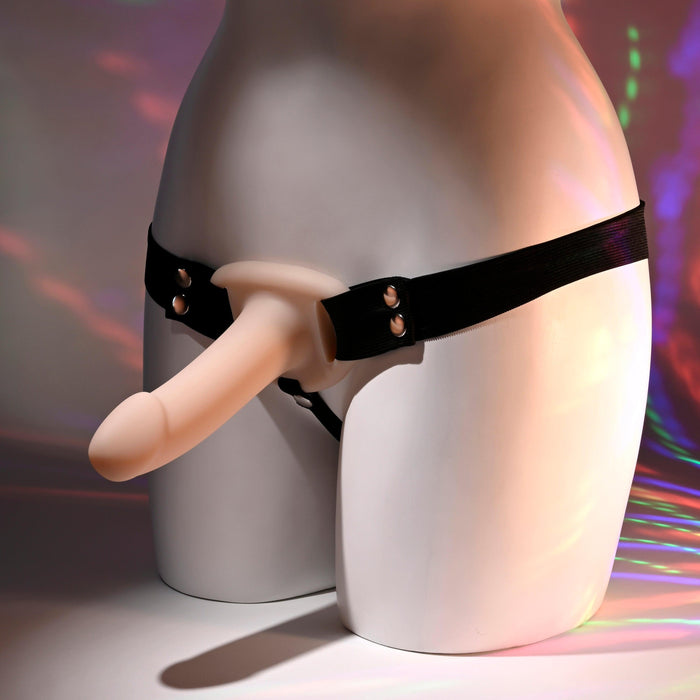 A mannequin displays the Our First Hollow Strap-On Dildo + Harness Set - Vanilla, made from flexible TPE, against a colorful backdrop with soft lighting.