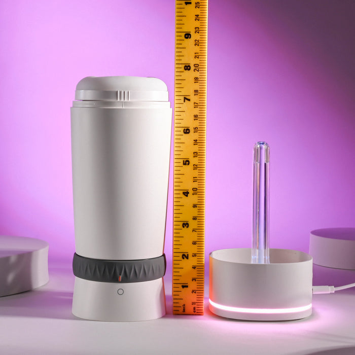 A Playboy Twist & Stroke Heated Vibrating Stroker with a white cylindrical shape sits beside a round base with a clear tube and yellow ruler showing its height, all set against a purple-lit background. The devices have a modern, minimalist design.