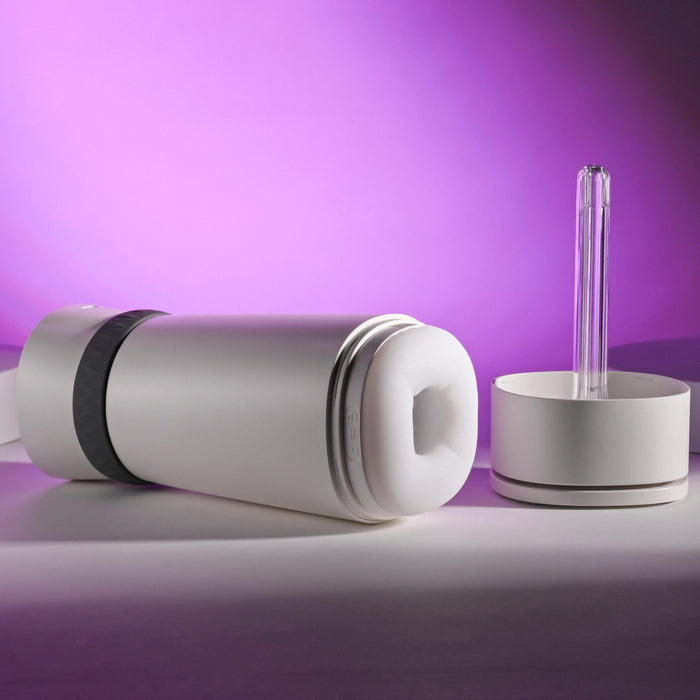 A sleek white water bottle with a gray grip lies next to a matching Playboy Twist & Stroke Heated Vibrating Stroker, both set against a striking purple gradient background.