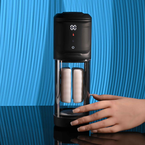A hand reaches for the Playboy Side Piece Heated Sliding Stroker, a black and transparent vibrating male masturbator with a digital display and two white filters, set on a blue textured background.