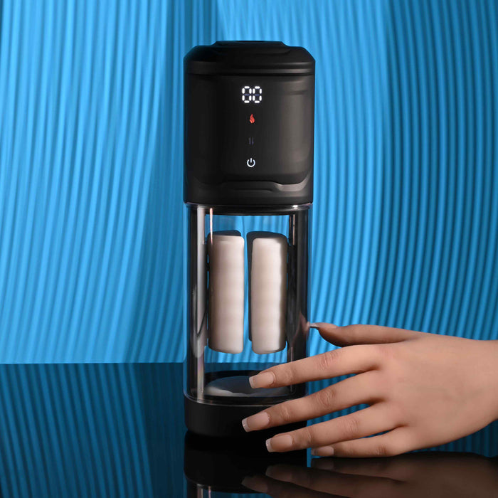 A hand reaches for the Playboy Side Piece Heated Sliding Stroker, a black and transparent vibrating male masturbator with a digital display and two white filters, set on a blue textured background.
