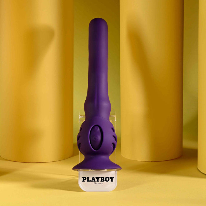 A purple condom is displayed next to the Wiggle It Silicone Wiggling Vibrator with a suction cup base.