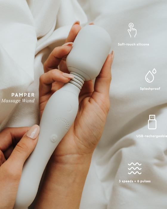 A hand holding a Pepper Pamper Massage Wand by Pepper with soft-touch silicone, water-resistant design, and USB rechargeable functionality, featuring multiple speeds and pulse settings for relaxation.