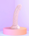 Starlight Pink Glitter 7 inch Silicone Dildo on pink riser with purple background 