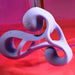 The Playboy Fantasy Cock Cage is a vibrating, rechargeable silicone toy in lavender with smooth, looping shapes and a small engraved bunny face, set against a pink and red gradient background.