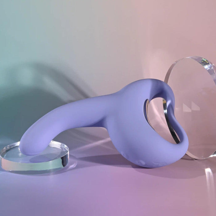 The Playboy Nice to Meet You Powerful Thrusting Vibrator with Handle in lavender, featuring a curved silicone design and looped handle, is shown on a pastel background between two clear round glass discs.