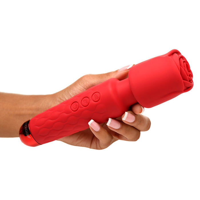A hand with manicured nails holds the Pleasure Rose Silicone Wand Vibrator with Rose Attachment, crafted from soft silicone and shaped like a blooming flower, featuring textured grip and side control buttons.