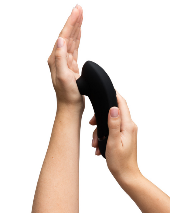 Caucasian hand holding Womanizer Next  Pleasure Air Clitoral Vibrator - Black pressed against other hand 