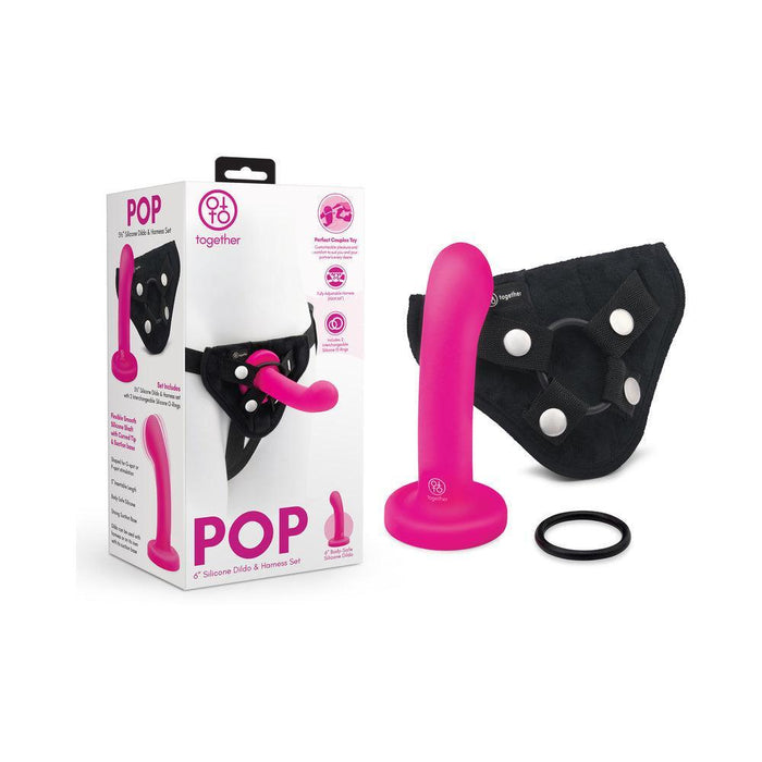 The Pop Strap on Dildo & Harness Set in Pink Silicone (5 inches) is shown with a pink dildo, black harness, and ring beside the packaging featuring product images and details.