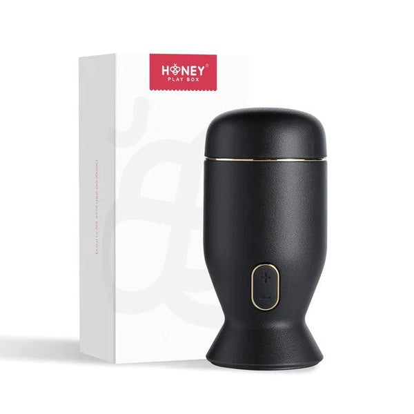 The Priti Automatic Rotating Penis Masturbator—a sleek, black, cylindrical toy with a gold accent and button—stands beside a white box labeled “Honey Play Box.”.