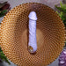 Lavender silicone vibrating dildo with realistic veins and a metallic finger loop base on a gold decorative plate.