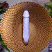 Lavender silicone vibrating dildo with realistic veins and a base finger loop, displayed on a gold textured bowl.