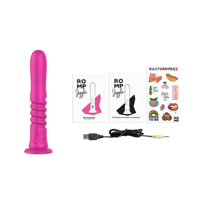 The ROMP Jiggle Thrusting Vibrator with Suction Base in pink, shown on a white background, comes with two instruction booklets, a USB charging cable, and a vibrant sticker sheet featuring fun designs and phrases.