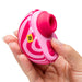 A hand holds the Romp Spin Small Discreet Pleasure Air Clitoral Stimulator, a pink and white striped, oval travel-size device with buttons, a circular opening, and a yellow "ROMP" label. It uses unique Pleasure Air technology for enhanced satisfaction.