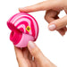 A person holds the Romp Spin Small Discreet Pleasure Air Clitoral Stimulator, a round, pink and red striped travel-size device, in one hand while pressing the button on top with the other.