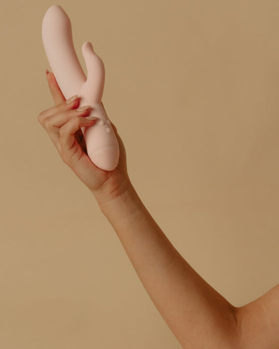 A hand elegantly displaying a Pepper Indulge Magnetic Rabbit Vibrator, featuring magnetic technology, against a neutral backdrop.