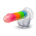 The Rainbow Rave Slim Glow in the Dark 6.5 Inch Silicone Dildo features a realistic, rainbow-striped design, textured detail, a translucent white suction base, and is strap-on harness compatible for versatile play.