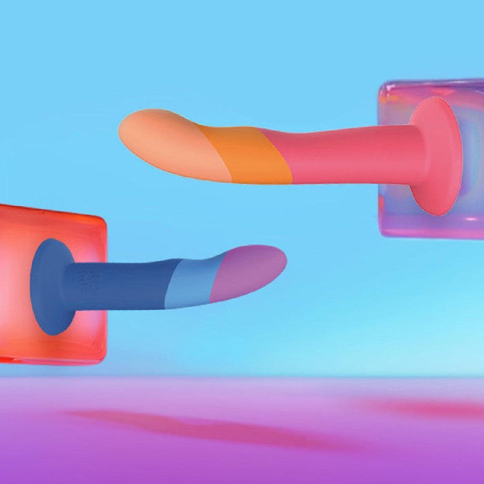 Two Romp Piccolo Sleek First Time 5 Inch Silicone Dildos with suction cups—one in red-orange and one in blue-purple—float against a pastel background. Ideal for enhancing g-spot or anal play experiences.