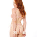 A woman with long red hair stands sideways in pink lingerie, wearing Peaches 'n Cream Fur Handcuffs—luxurious peach bondage cuffs linked by a short chain—against a white background.