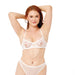 A woman with long red hair poses confidently in white sheer lingerie, showcasing Peaches 'n Cream Pearl Nipple Clamps, her hands behind her head against a plain white background.