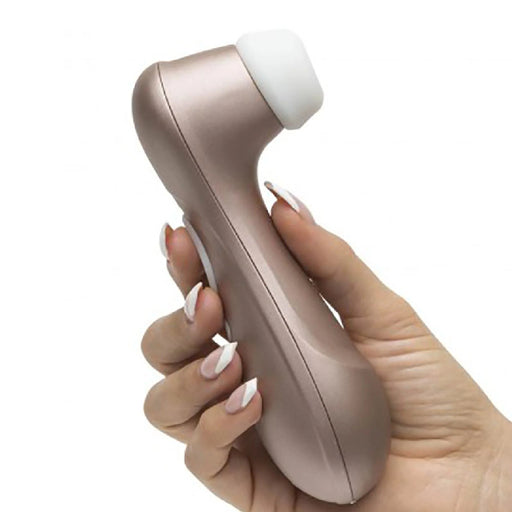 A manicured hand holds the Satisfyer Pro 2 Waterproof Pressure Wave Clitoral Stimulator in rose gold, with a white silicone tip, shown against a plain white background.