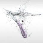 A lilac Satisfyer Pro 2 Waterproof Pressure Wave Clitoral Stimulator plunges into clear water, sending droplets and ripples across a light grey background.