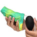 A person holds the Siphon Green Tentacle Squirting Penis Enhancer, featuring a vibrant blend of green, yellow, and blue textures, in one hand while squeezing the attached black bulb pump with the other.