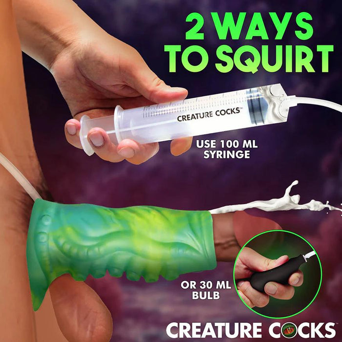 A hand holds a Siphon Green Tentacle Squirting Penis Enhancer with fluid spraying out. Text reads: “2 ways to squirt: use 100 ml syringe or 30 ml bulb. Fantasy sleeve Creature Cocks.”.