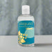 An 8.5 oz (255 ml) bottle of Sliquid Tsunami Ultra Thick Water Based Lubricant features water-based carrageenan, a teal label with abstract sun and waves, a white flip-top cap, and is set against a blurred background for added mystery.
