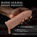 A hand holds the Star Studded Silicone Penis Extender - 6.5 Inch Closed Ended, nude with star patterns and a strap, against a faint American flag. Text: "Ride Hard. Shine Bright." Benefits: added length, more girth, increased confidence.
