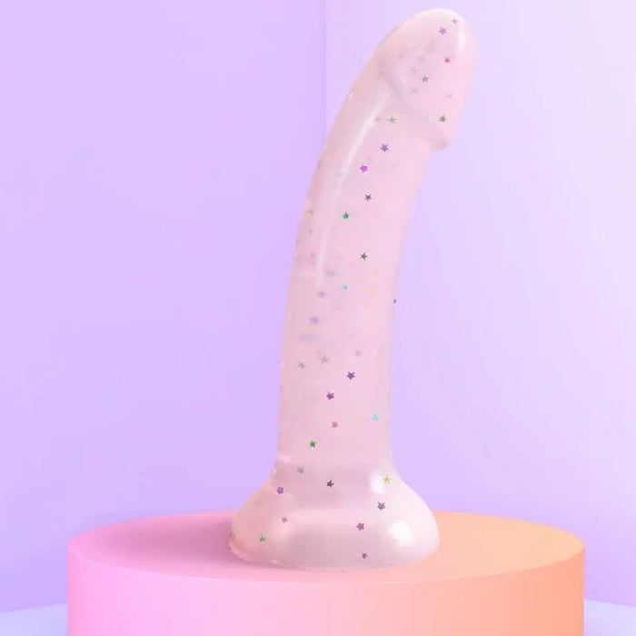 The Starlight Smooth 7 Inch Pink Glitter Silicone Dildo with Suction Cup, featuring a curved shape, stands upright on a pastel pedestal against a soft purple background.