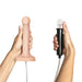Two hands hold medical devices: the left grips the Strap-On-Me 6 Inch Silicone Squirting Dildo in vanilla, the right holds a black controller. A white cable connects them, set against a clean white background.