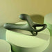 The Strap Tap & Go Girth Enhancer & Tapping Vibrator, a green silicone cock ring with ergonomic curves and loops, is displayed on round, light green platforms against a softly lit background.