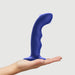 A hand holds the Strap on Me Curved G-Spot Tapping Blue Silicone Dildo, featuring a curved shape and flared base, isolated on a plain white background.