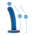 The Surrender Sleek Slim 5.75 Inch Blue Silicone Beginner & Pegging Dildo features a curved, metallic-blue body with a flared base, 1-inch diameter, 5.25-inch insertable and 5.75-inch total length—ideal for beginners or pegging play.