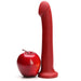 A shiny red apple sits next to the Tantus Hook Long 9 Inch G-Spot or Prostate Red Silicone Dildo—strap-on harness compatible—standing upright on a white background.