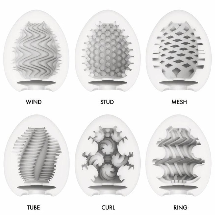 The Tenga Egg Disposable Penis Masturbation Sleeves - Wonder Variety Pack of 6 includes uniquely textured, discreet white sleeves labeled WIND, STUD, MESH, TUBE, CURL, and RING—perfect for travel pleasure.
