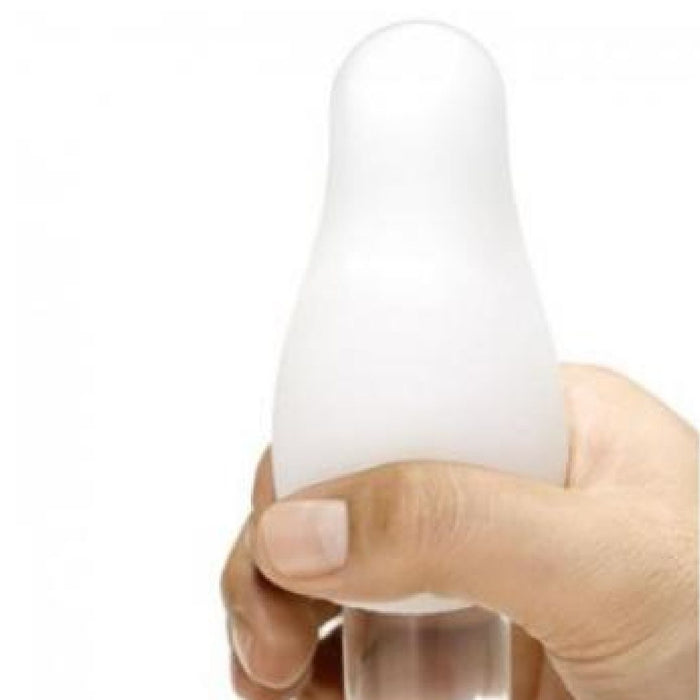 A hand holds a white, rounded, cone-shaped object with a smooth surface—it’s the Tenga Egg Disposable Penis Masturbator - Wavy, known for its discreet and minimalist design as a popular travel sex toy.