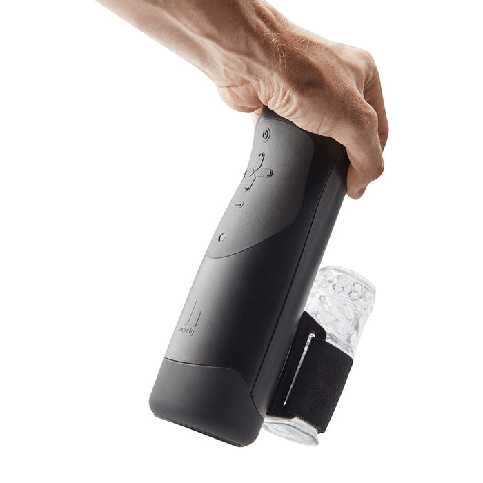 A hand holds The Handy Adjustable Hand Job Penis Stroker, a black interactive male masturbator with buttons and a clear cylindrical attachment secured by a strap, set against a plain white background.