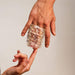 A clear, textured Handy Mermaid Collection Coral Sleeve - Intense Sensations, made from stretchy TPE, is wrapped around two fingers as another hand softly touches an exposed finger, all set against a neutral background.