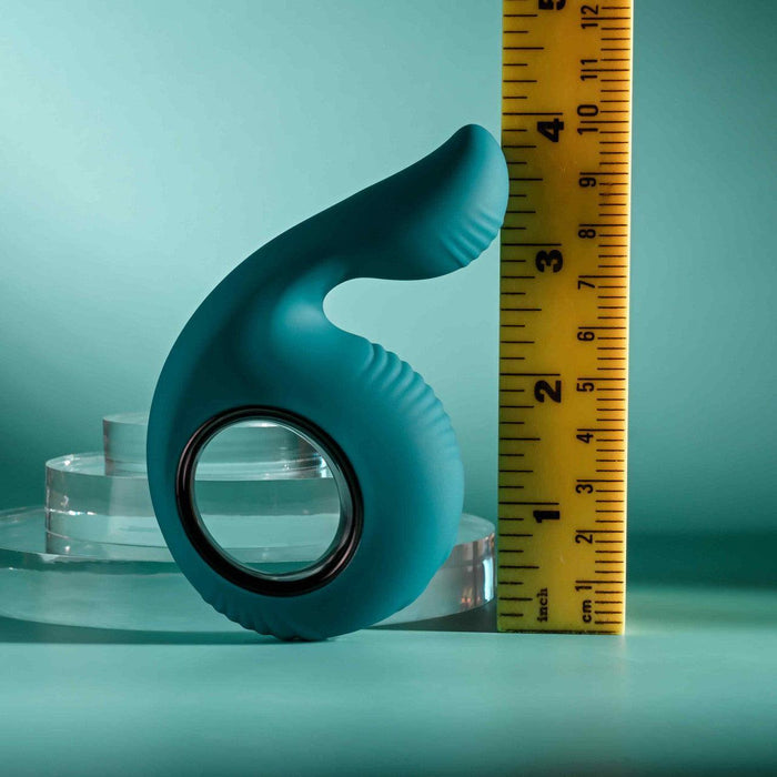 Teal silicone shallow penetration vibrator with a finger loop and textured thumb-shaped tip next to a ruler.