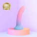 The Utopia Sleek 7 Inch Pink and Blue Ombre Silicone Dildo with Suction Cup stands on a round platform in a softly lit, minimal room. An "XBIZ Awards Winner" gold badge appears at the top left—ideal for prostate or G-spot play.
