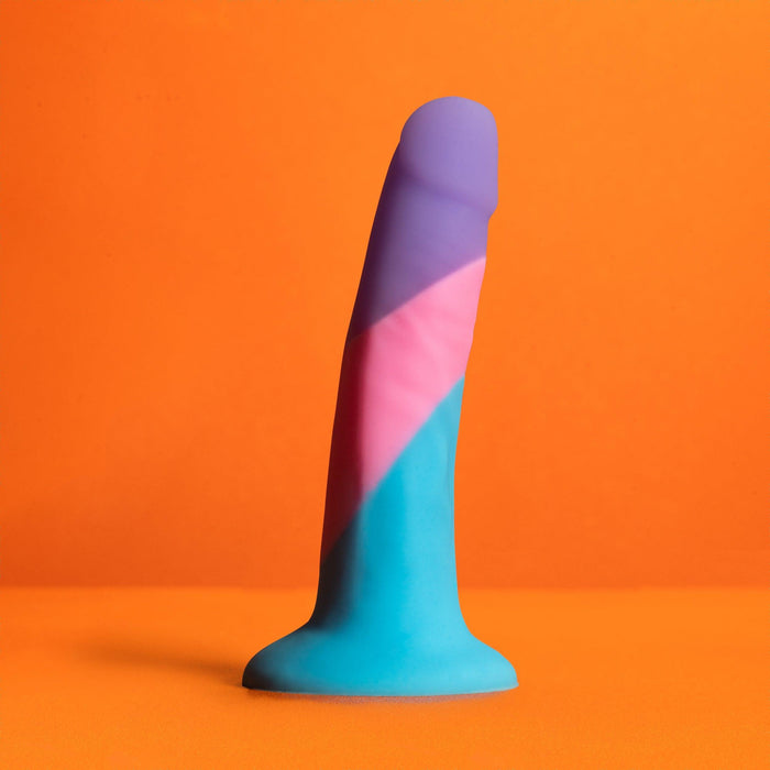 The Vision of Love Tapered 5.5 Inch Silicone Suction Cup Dildo, crafted from platinum silicone in blue, pink, and purple hues, stands upright on an orange background—an ideal choice for beginners.