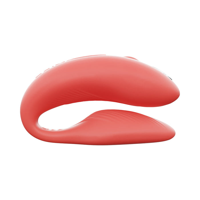 The We-Vibe Chorus Remote & App Controlled Couples' Vibrator in Coral is a red, curved silicone toy with two parallel, rounded ends—one larger and one smaller—designed for an adjustable fit and modern look.